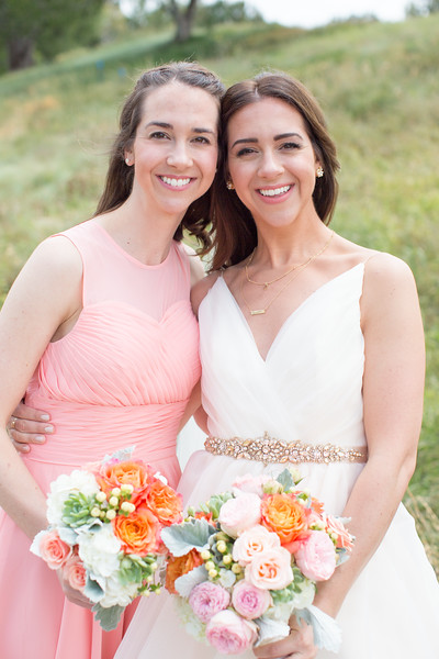An image of the bride and one bridesmaid holding a white, orange and light pink rose bouquet for the Cortez Wedding