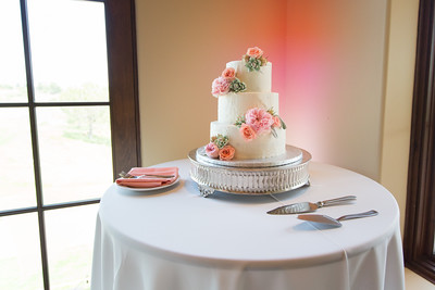 An image of white wedding cake decorated with pink and orange flowers