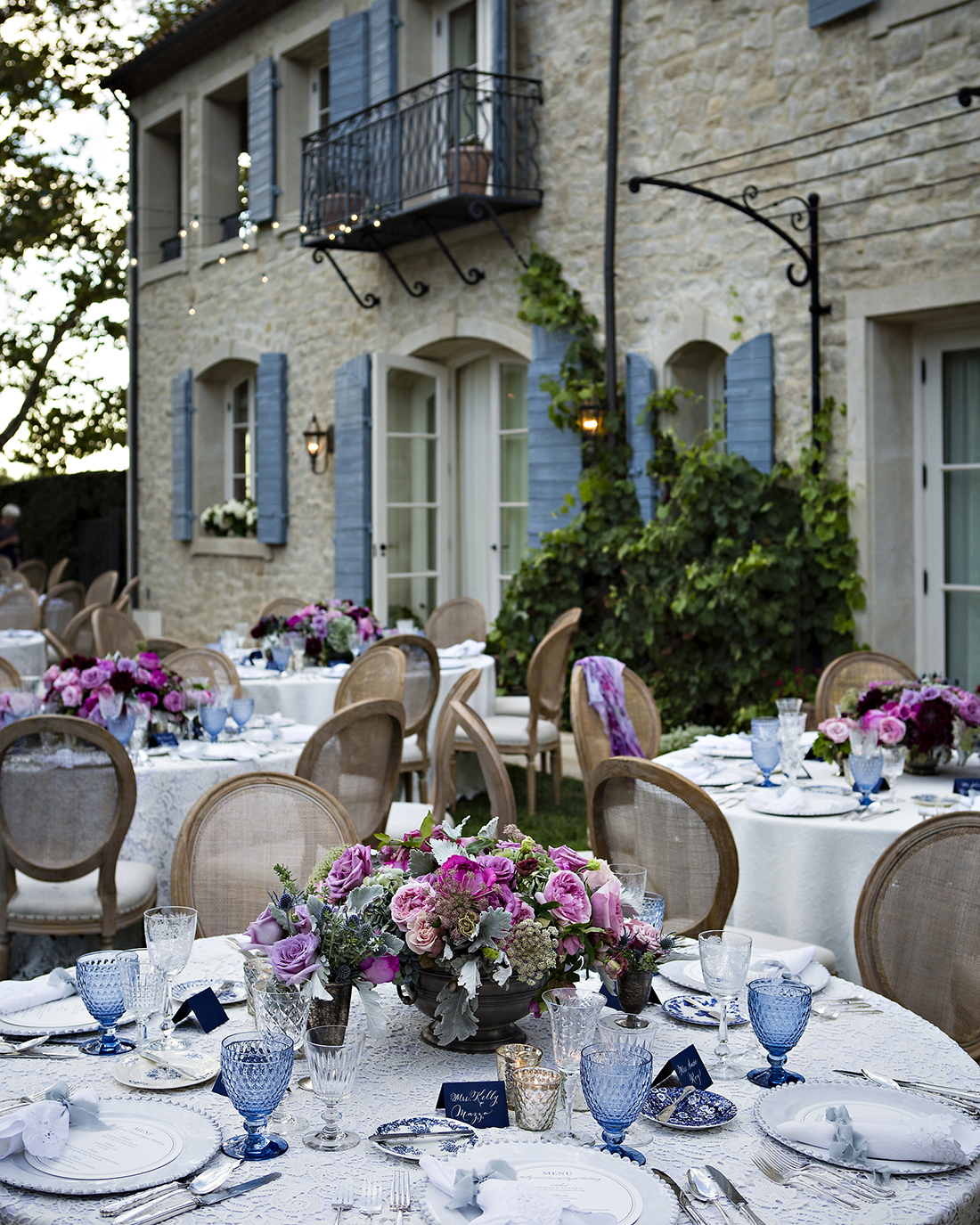 An image of a blue colored dining set up with magenta rose floral center piece