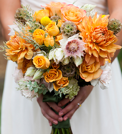 An image of a orange rose and dahlia wedding bouquet