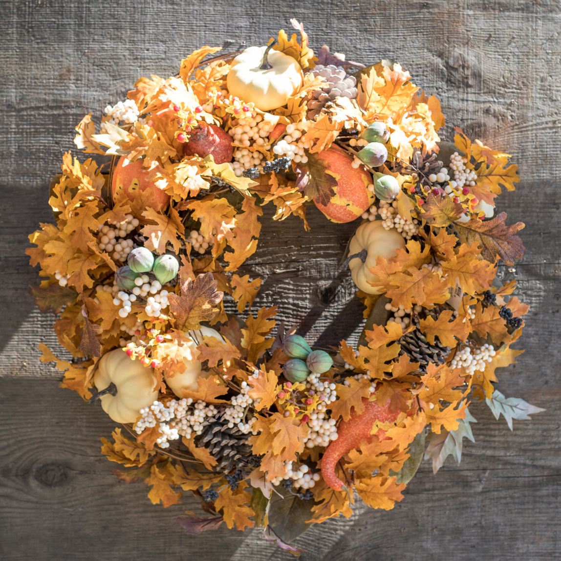 An image of orange, fall, leaves, pinecones, white pumpkin and orange squash wreath