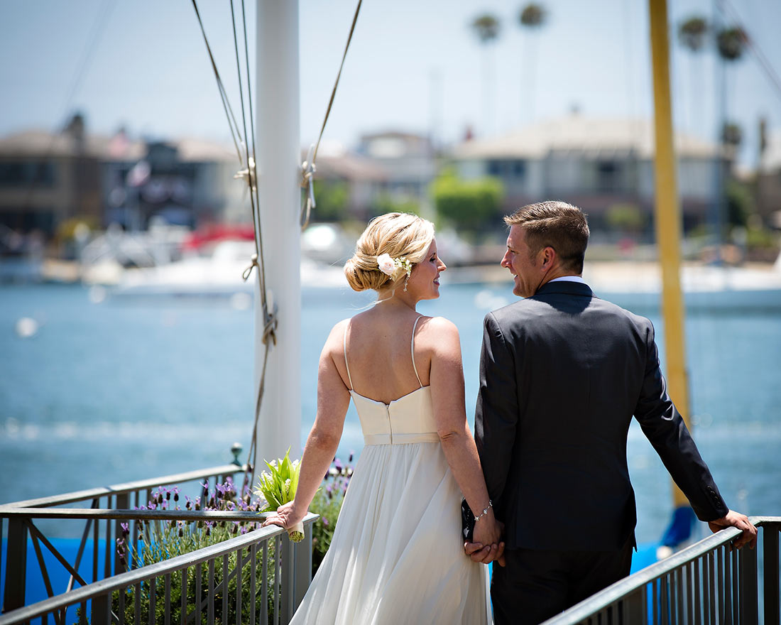 An image of the backs of the bride and groom in front of the harbor