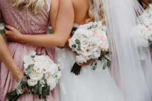 An image of a bride and bridesmaid holding white rose bouquets